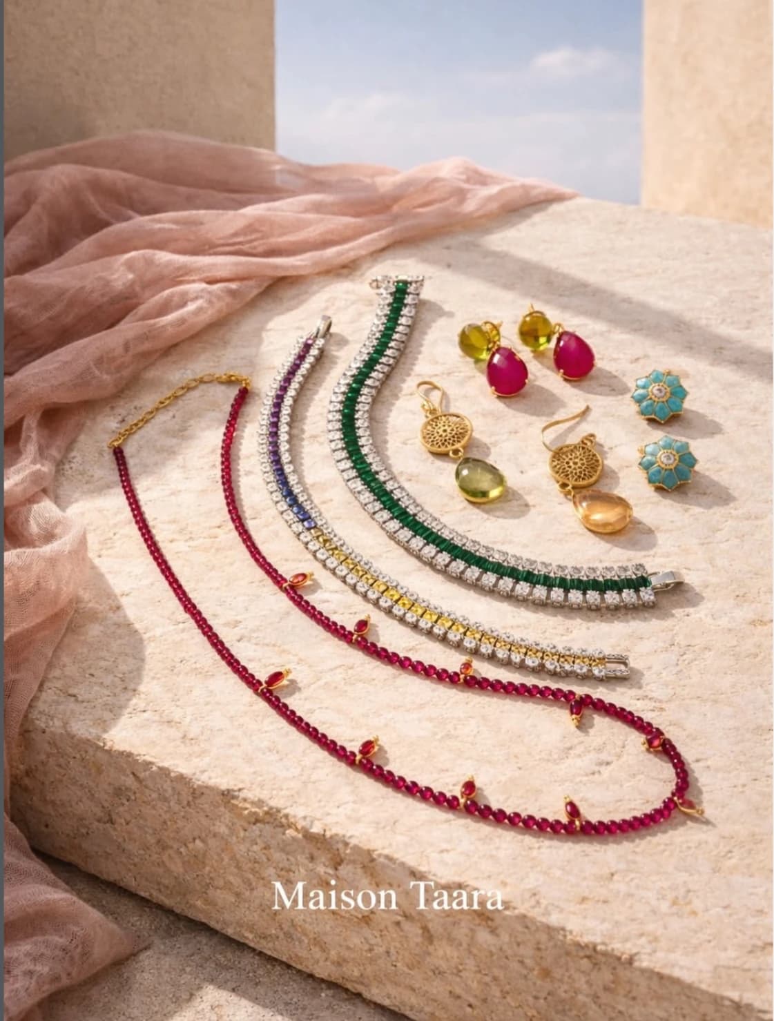 Maison Taara jewellery arranged on soft blush fabric.